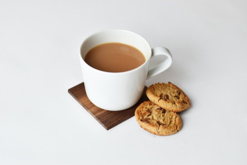 mug with tea and two cookies on brown coaster